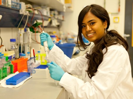 Ein junges Mädchen mit dunklen Haaren arbeitet mit einer Pipette in einem Labor